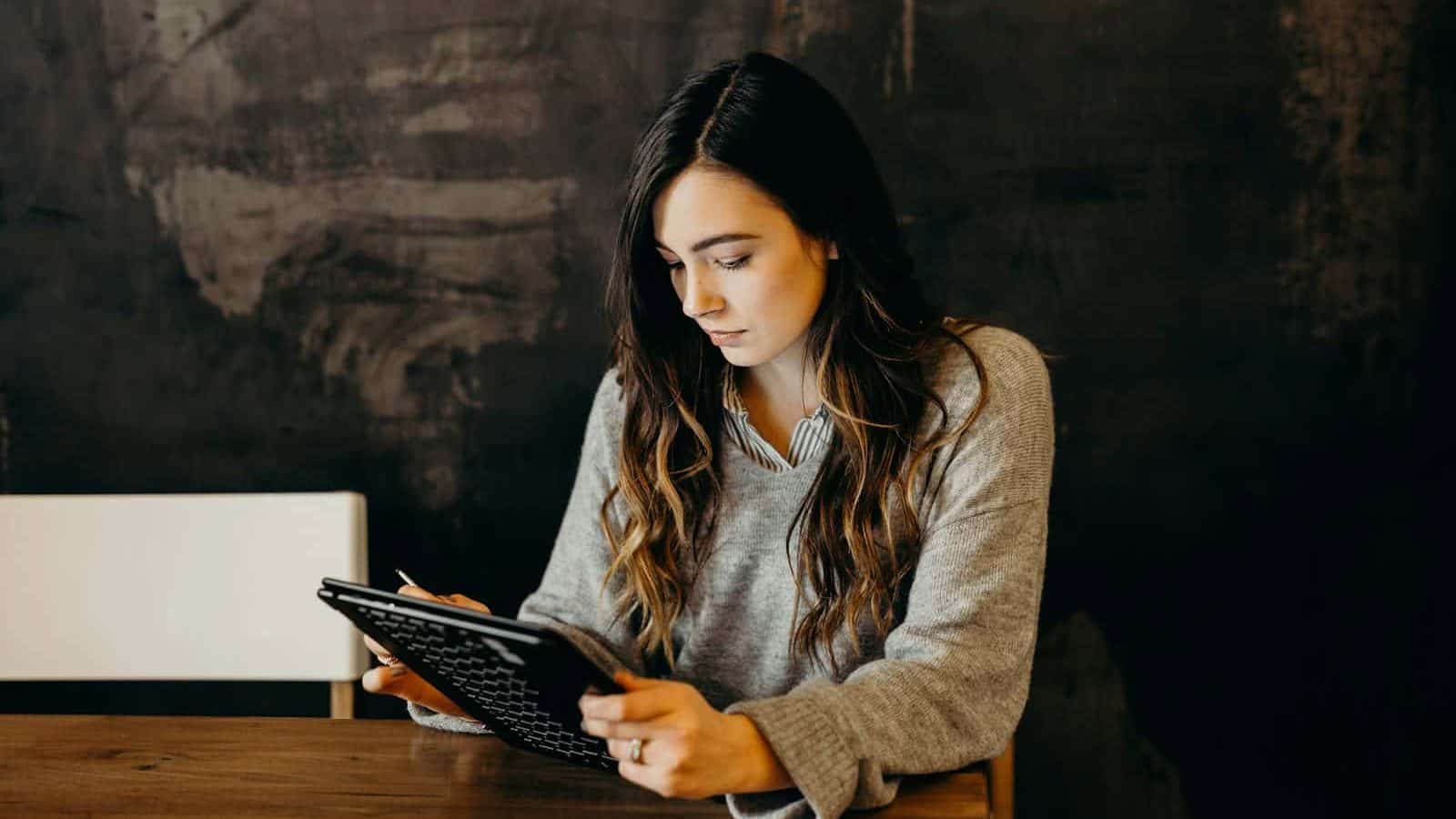 woman wearing white dress shirt using holding black leather case on brown wooden table